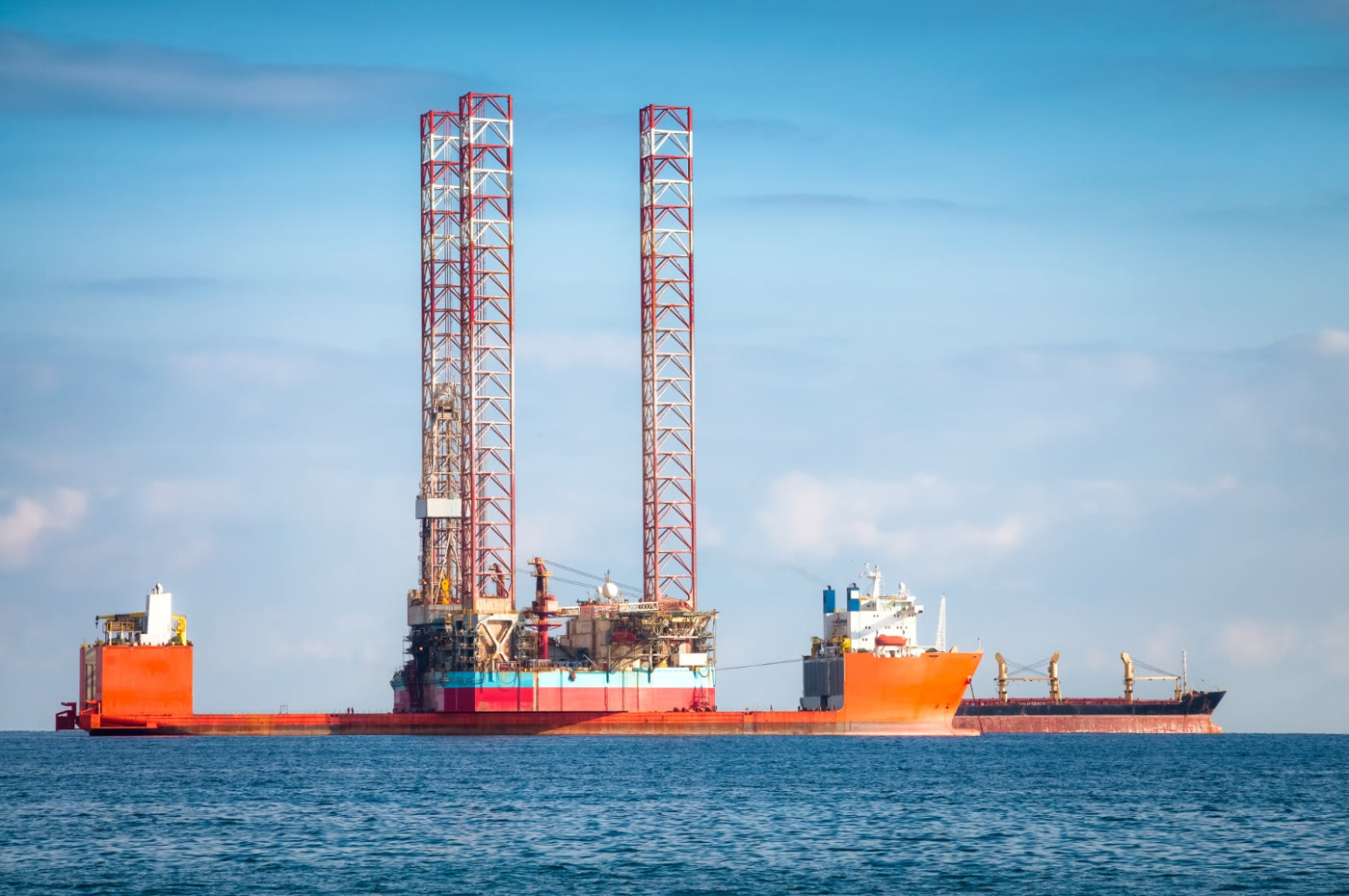 Jack-up drilling rig under tow by a support vessel at sea
